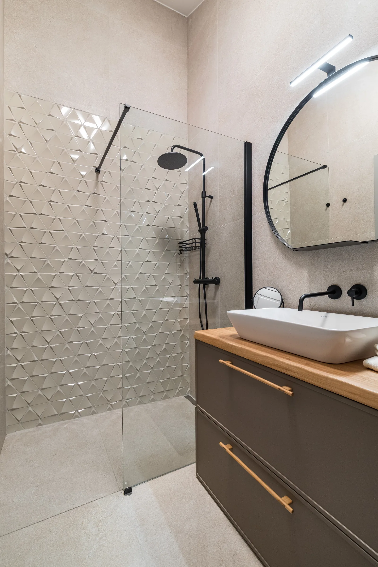 Bathroom in textured stone tile with a brass-handled oak vanity