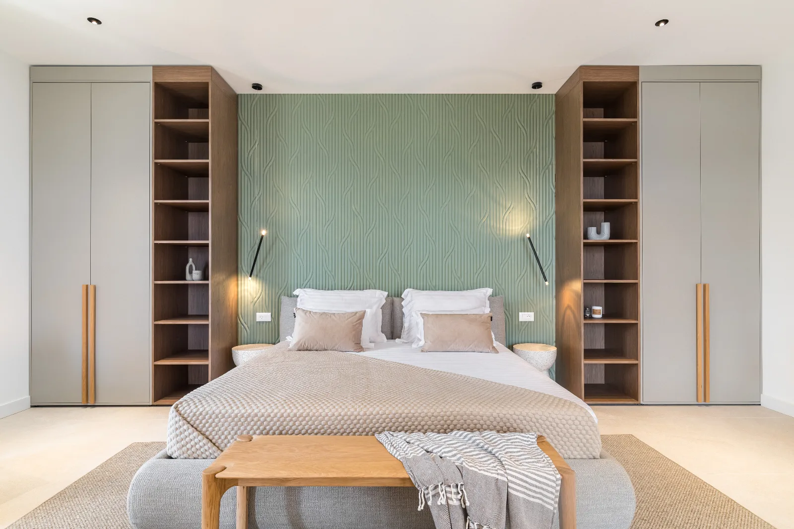 Master bedroom framed by matching oak wardrobes and a patterned green headboard wall
