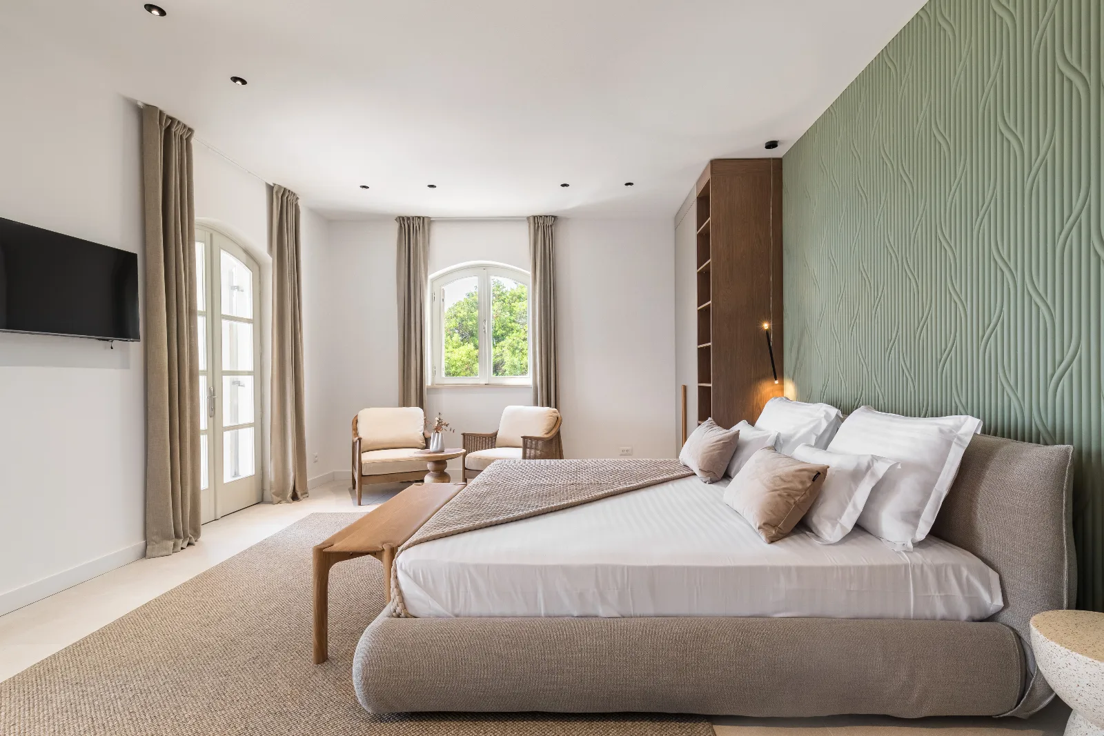 Bedroom with a carved green panel wall, upholstered bed and arched glass doors