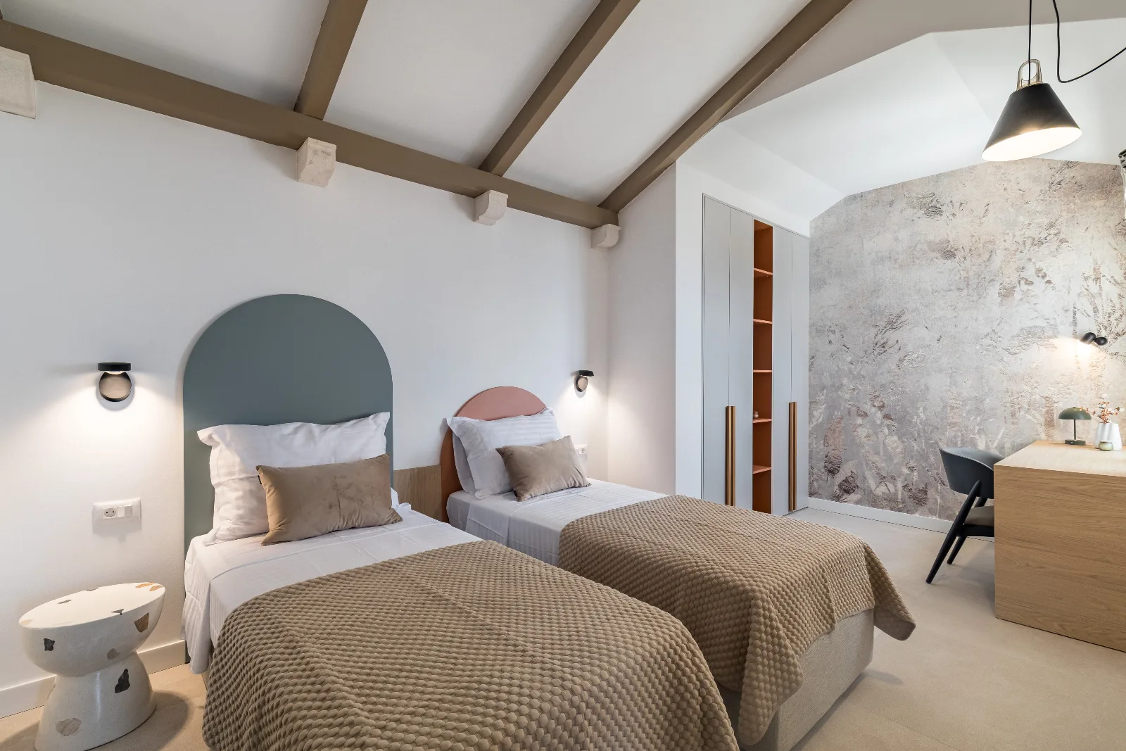 Twin room with arched headboards, layered textiles and a plastered feature wall