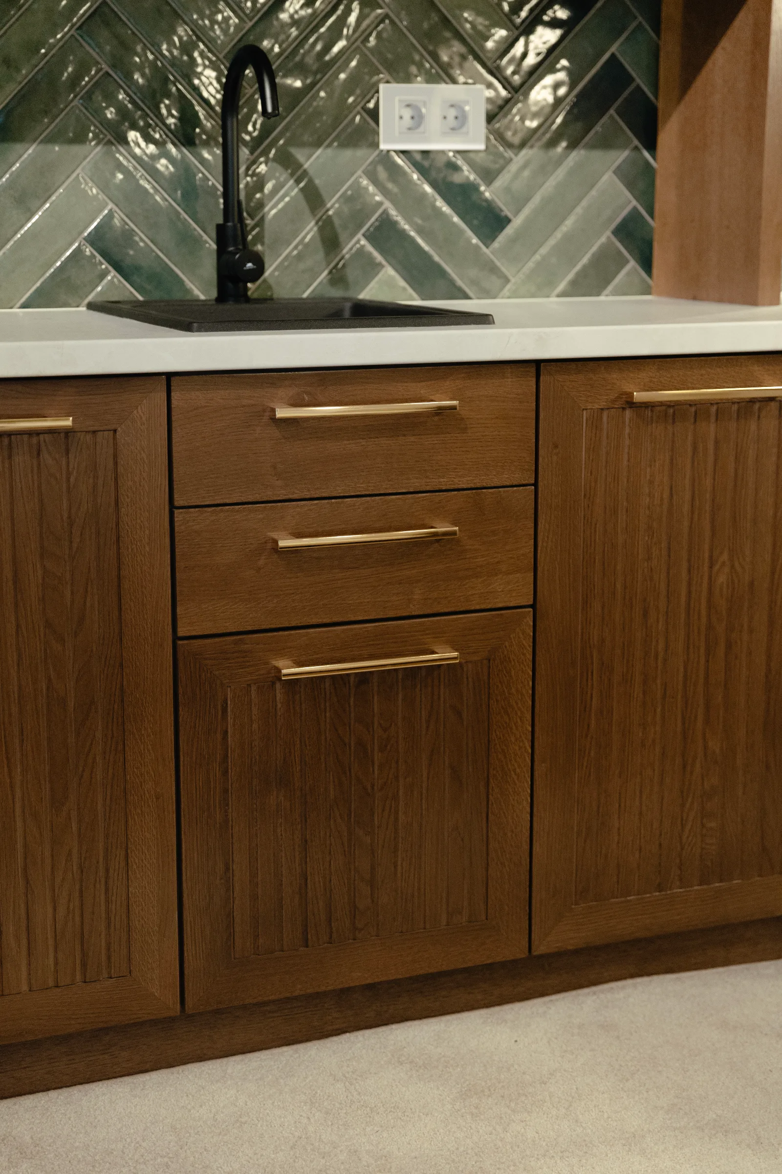 Fitted oak kitchen cabinets with brass pulls under a stone worktop